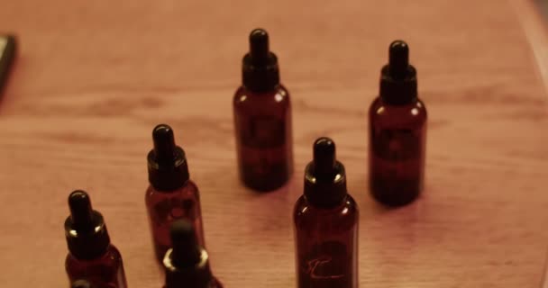 ダークルームで香水を作成するために木の机に置かれた異なる芳香性エッセンシャルオイルを用いた高角度ハンドヘルドショット — ストック動画