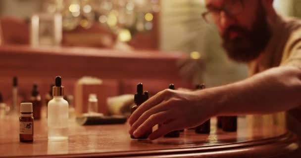 Gözlüklü Sakallı Bir Erkek Kimyagerin Elinde Çeşitli Şişelerle Ahşap Masada — Stok video