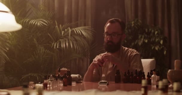 Odaklanmış Erkek Kimyagerin Gerçek Zamanlı Resmi Loş Işıkla Masada Oturuyor — Stok video