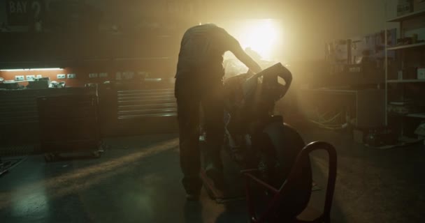 修车过程中 机修工在昏暗的阳光照射下 将摩托车放在车胎上的实景手持镜头 — 图库视频影像