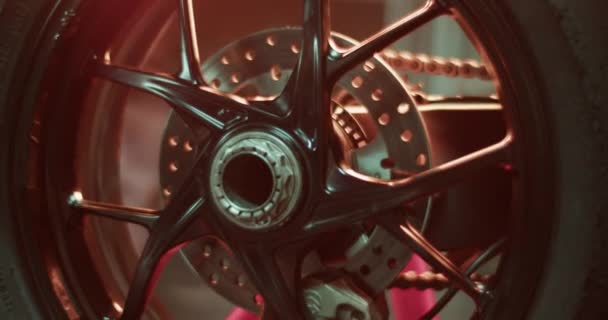 赛前车库里装有金属盘偶联橡胶和链条的现代摩托车车轮的实时闭合 — 图库视频影像