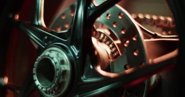 赛前车库里装有金属盘偶联橡胶和链条的现代摩托车车轮的实时闭合 — 图库视频影像