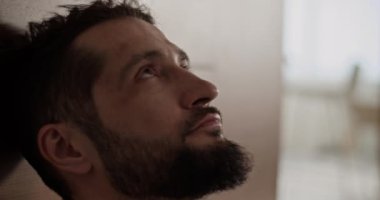 Depresyonda olan sakallı, yetişkin bir erkeğin çözümler üzerinde düşünürken yaşadığı sorunlara yakından bakmak ve arka planda bulanıklığa rağmen daireye bakmak.