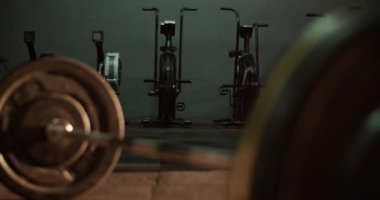 Bulanık halterli, demir ağır plakalı ve spor salonunun zeminine sıkıca kenetlenmiş bir halterin gerçek zamanlı görüntüsü.
