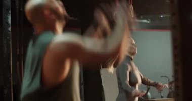 Kimliği belirsiz kaslı bir adamın spor salonunda genç bir bayanla barfiks çekmesi ve antrenman yapması ve ekipmanla ip atlamasıyla eş zamanlı görüntüsü.