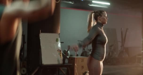 肌肉发达的无名饲养员在酒吧拉车 用年轻女子跳绳在健身房装备训练的实时侧视图 — 图库视频影像