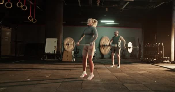 スポーツウェアのアクティブな男性と女性のボディビルダーは ジムでの激しいトレーニング中にバーベルでクリーンでジャーク重量挙げ運動を行います — ストック動画