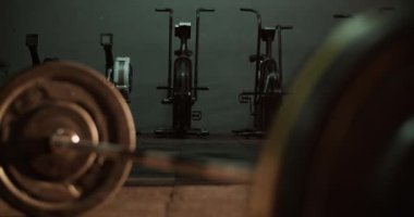 Bulanık halterli, demir ağır plakalı ve spor salonunun zeminine sıkıca kenetlenmiş bir halterin gerçek zamanlı görüntüsü.