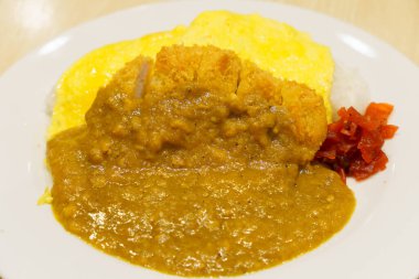 Bulanık arkaplanlı beyaz bir tabakta körili pirinçli yakın plan.