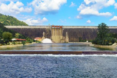 Large water reservoir dam wall releasing water with beautiful sky