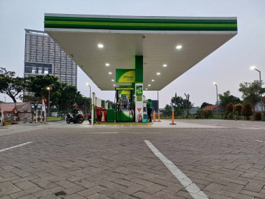 A modern BP petrol station in Tangerang, Indonesia, stands ready to serve motorists, offering fuel and convenience. The clean design and bright branding create an inviting stop for travelers on their journey. clipart