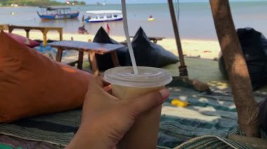 Kahve fincanını samanla tutarken