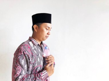 Asyalı Müslüman adam izole edilmiş arka planda plastik su şişesi tutuyor.