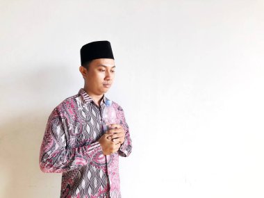 Asyalı Müslüman adam izole edilmiş arka planda plastik su şişesi tutuyor.