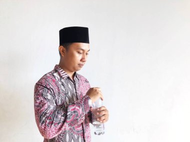 Asyalı Müslüman adam izole edilmiş arka planda plastik su şişesi tutuyor.