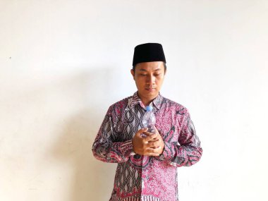 Asyalı Müslüman adam izole edilmiş arka planda plastik su şişesi tutuyor.