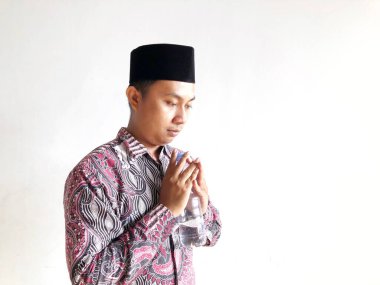 Asyalı Müslüman adam izole edilmiş arka planda plastik su şişesi tutuyor.