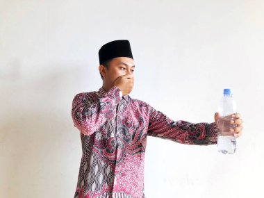 Geleneksel kostümlü, elinde bir bardak suyla yakışıklı bir müslüman..