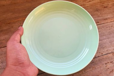 Beyaz arka planda boş bir tabağı tutan el.