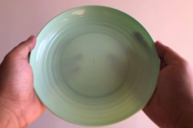 Beyaz arka planda boş bir tabağı tutan el.