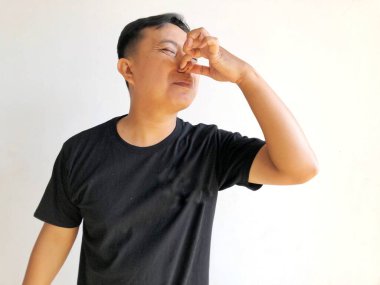 Genç Asyalı adam burnunu eliyle kapatıyor..