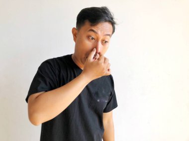 Genç Asyalı adam burnunu eliyle kapatıyor..