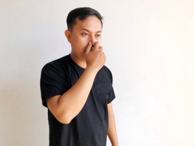 Genç Asyalı adam burnunu eliyle kapatıyor..