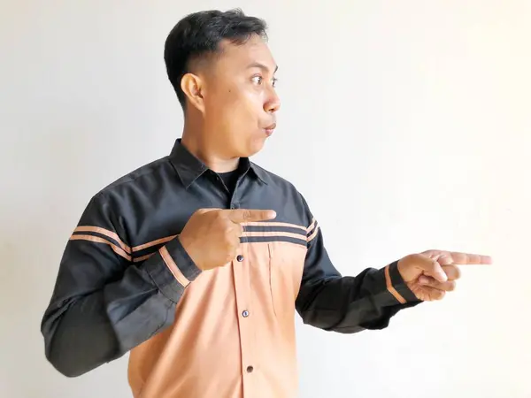 Siyah tişörtlü genç Asyalı adam tek parmakla işaret ediyor.