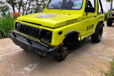 Jepara, 10 Agustus 2024 - Sarı Suzuki Samuray arabası lastik değiştiriyor