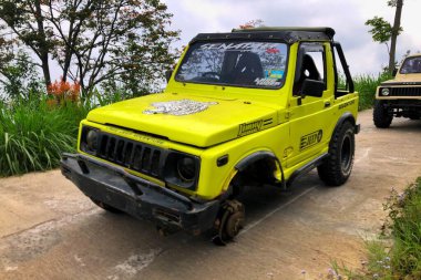 Jepara, 10 Agustus 2024 - Sarı Suzuki Samuray arabası lastik değiştiriyor