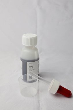 Şurup şurubu pipeti ve ilaç şurubunun arka planında ölçü kabı var.