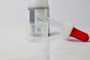 Şurup şurubu pipeti ve ilaç şurubunun arka planında ölçü kabı var.