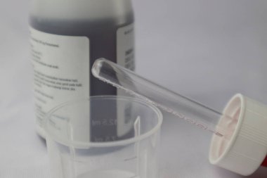 Şurup şurubu pipeti ve ilaç şurubunun arka planında ölçü kabı var.