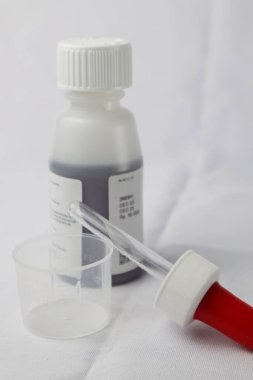 Şurup şurubu pipeti ve ilaç şurubunun arka planında ölçü kabı var.