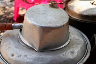 Bahçe arka planında kaynayan eski bir su kabı.     