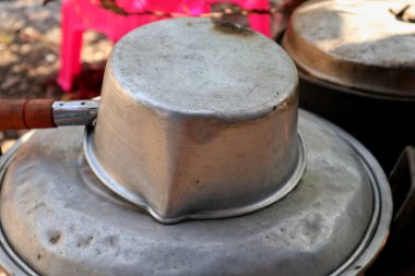 Bahçe arka planında kaynayan eski bir su kabı.     