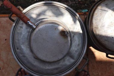 Büyük metal bir kase, kaşık ve metal bir su kabı.