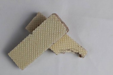Beyaz arkaplanda izole edilmiş rastgele gofret yığını. Çikolatalı bisküvi gofretleri lezzetli çikolatalı kremayla dolu. Kuru ve çıtır gofretler yemek için hazır. Isırılmış gofret