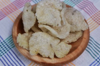 Close-up of jengkol crackers served on a wooden plate clipart