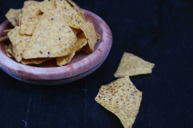 Tahta kasedeki mısır cipsi siyah arka planda izole edilmiş.