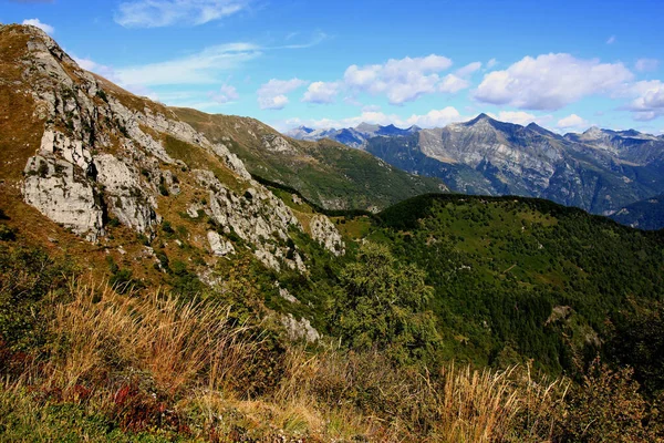 スイスのロカルノ近くにあるCimetta山の雲と青い空に向かって前景に山と緑の丘を持つ風景のパノラマビュー — ストック写真