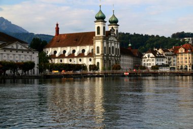 Lucerne, İsviçre-09.06.2018: Lucerne Gölü kıyısı manzaralı tarihi binalar, demir köprü ve Cizvitenkirche
