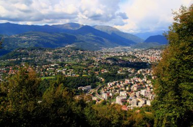 Panoramic view of the mountains and a city at their feet from Mount San Salvatore in the city of Lugano, in southern Switzerland