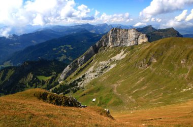 Ön planda bir dağ ve arka planda uzun dağ sıraları olan manzara, İsviçre 'nin Lucerne yakınlarındaki Pilatus Dağı' nda bulutlu mavi bir gökyüzüne karşı uzanır.