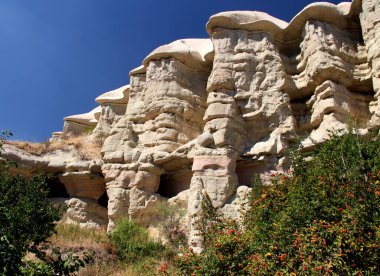 Türkiye 'nin başkenti Kapadokya' daki Goreme ve Uchisar kasabaları yakınlarındaki Güvercin Vadisi 'nde açık mavi gökyüzü üzerinde inanılmaz şekilli dağlar.