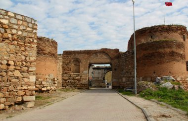 Kapılardan birinin yuvarlak kuleleri ve İznik 'in tarihi bölümünü çevreleyen bir duvarı mavi bulutlu gökyüzüne karşı.