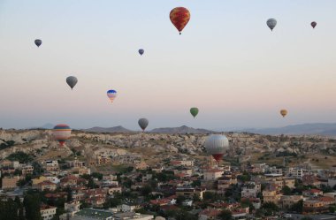 Kapadokya 'da (Türkiye) Goreme kasabası yakınlarındaki bir vadi üzerinde şafakta sıcak hava balonları uçuşu