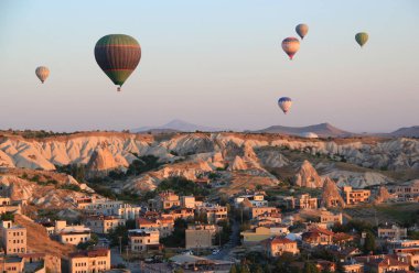 Kapadokya 'da (Türkiye) Goreme kasabası yakınlarındaki bir vadi üzerinde şafakta sıcak hava balonları uçuşu