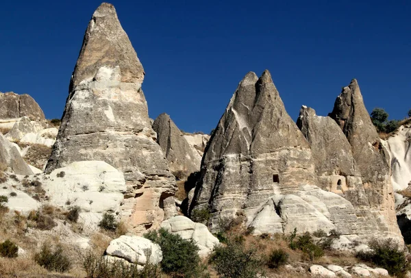 キノコの形をした山々 妖精の煙突とも呼ばれます の風景は トルコのカッパドキアのゴレの町の近くのゼミ渓谷の明るい青空に対して洞窟の中にあります — ストック写真
