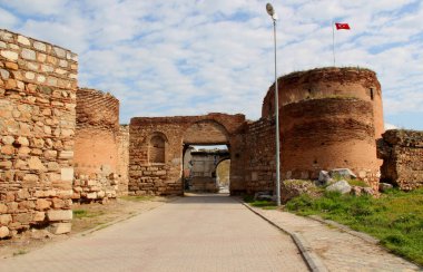 Kapılardan birinin yuvarlak kuleleri ve İznik 'in tarihi bölümünü çevreleyen bir duvarı mavi bulutlu gökyüzüne karşı.
